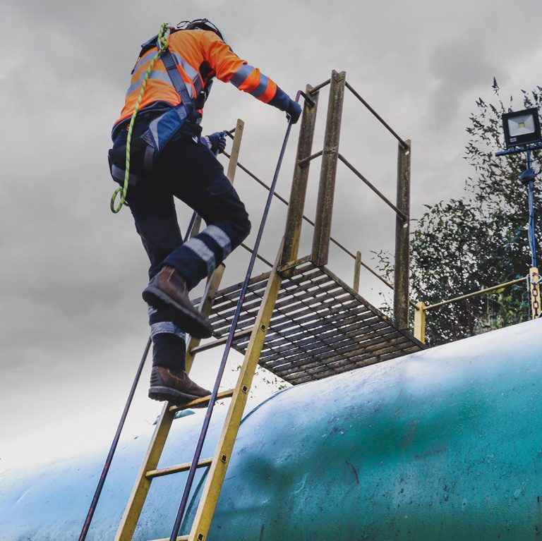RSM worker climbing a ladder up to a fuel tank