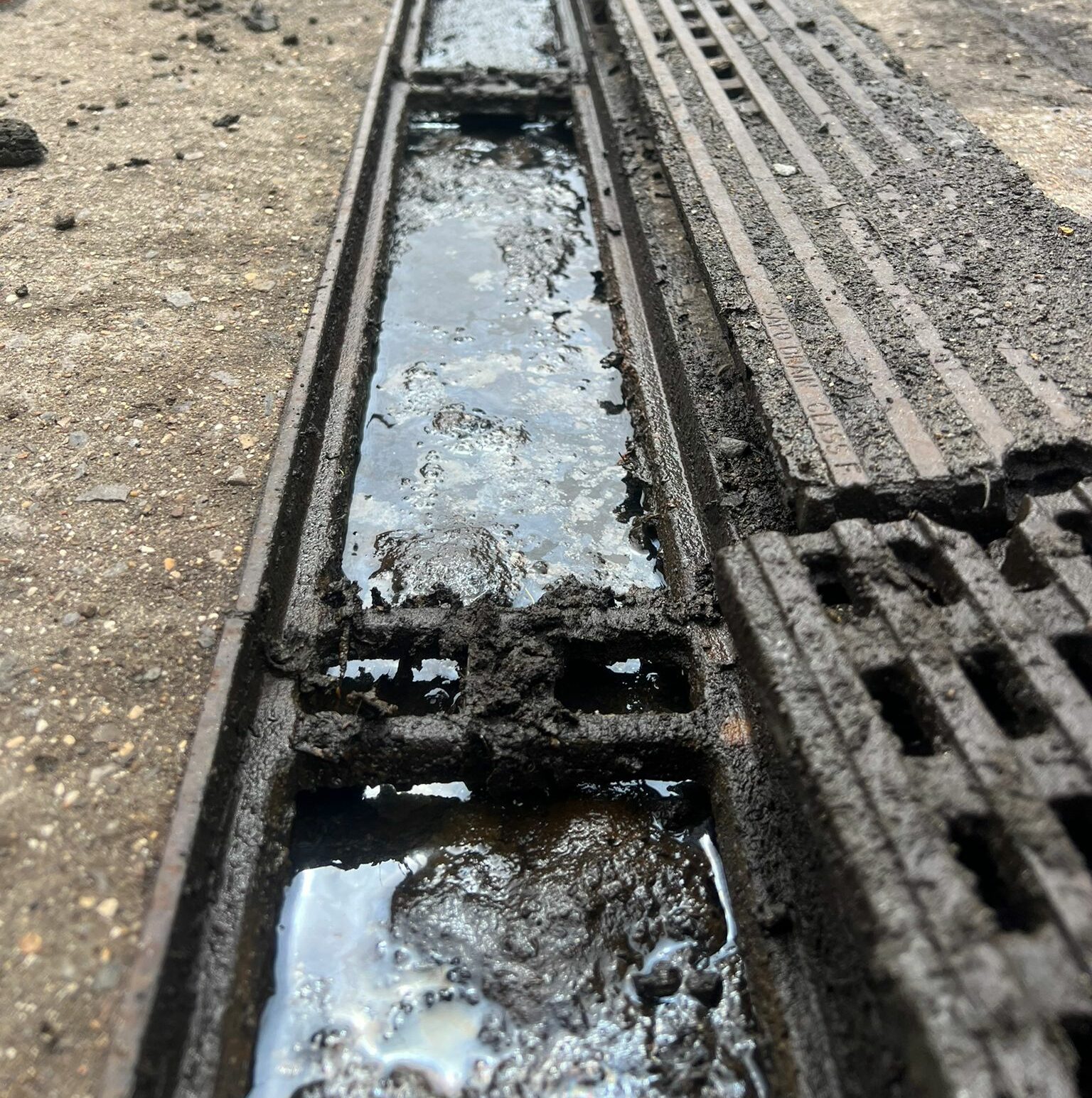 outside clogged drainage with dirty brown water in drain about to overflow