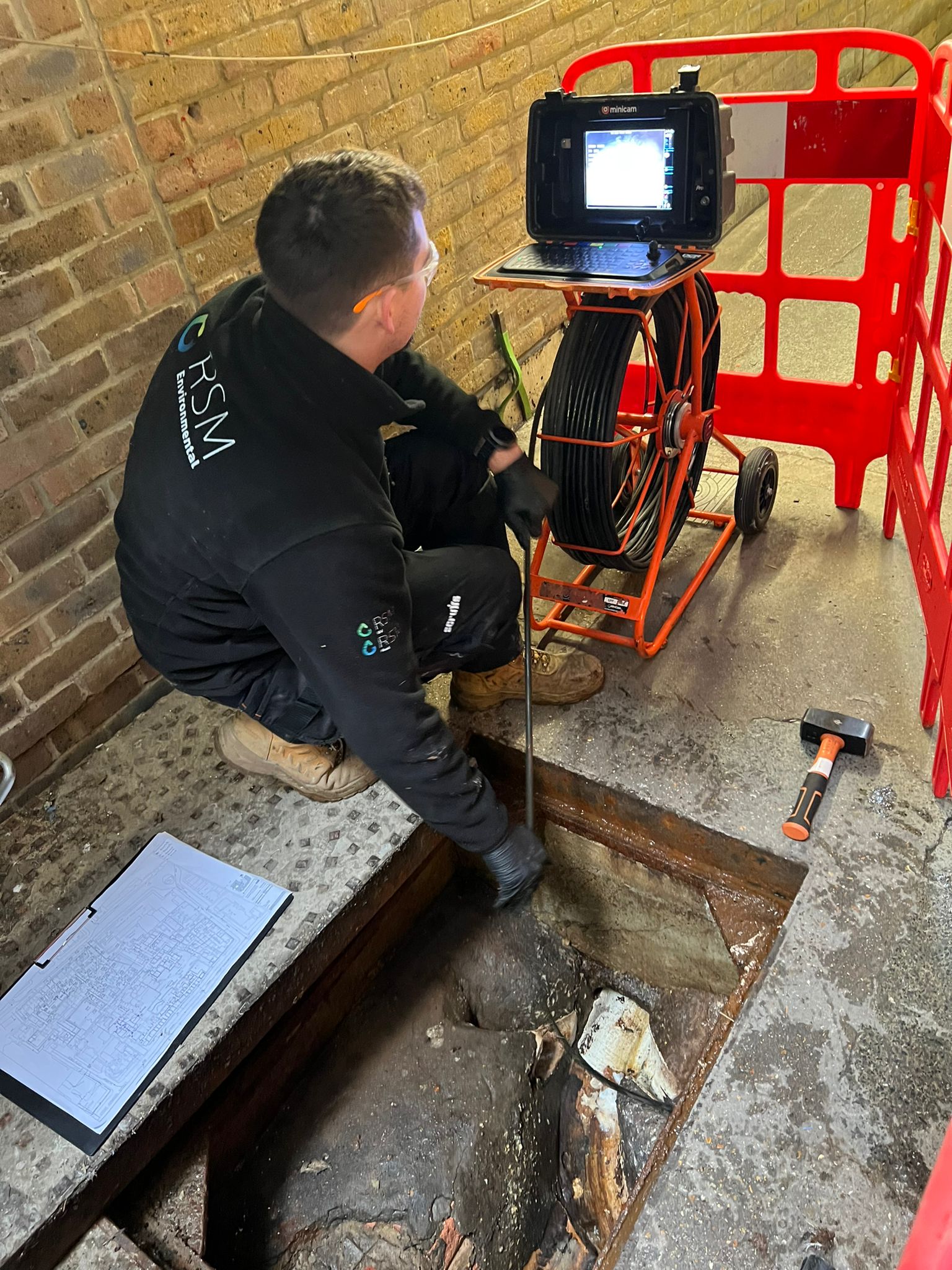 Engineer using machine with pipe in worksite's drainage to survey connectivity