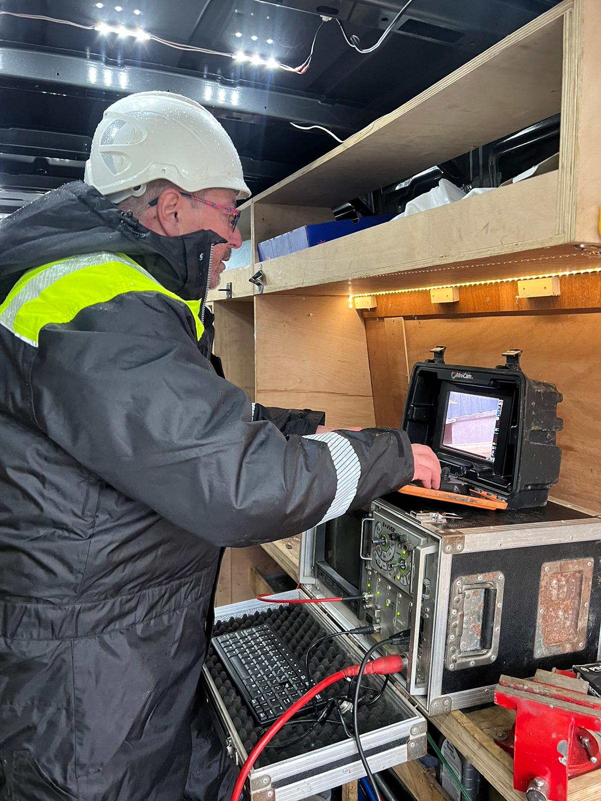 Engineer in hard hat using computer to survey drainage
